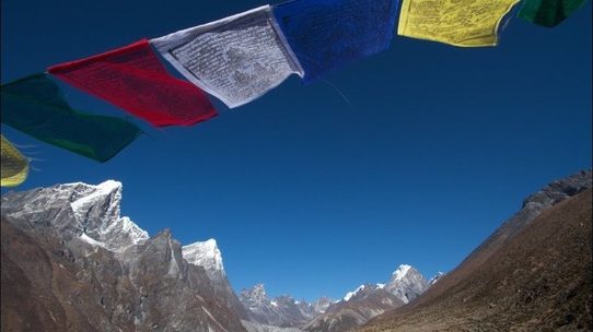 Prayer flags strung against the peaks of the Himalaya