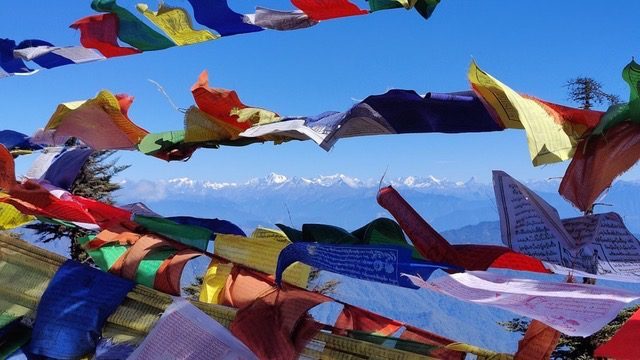 Prayer flags in the wind above a view of the Bhutanese Himalaya
