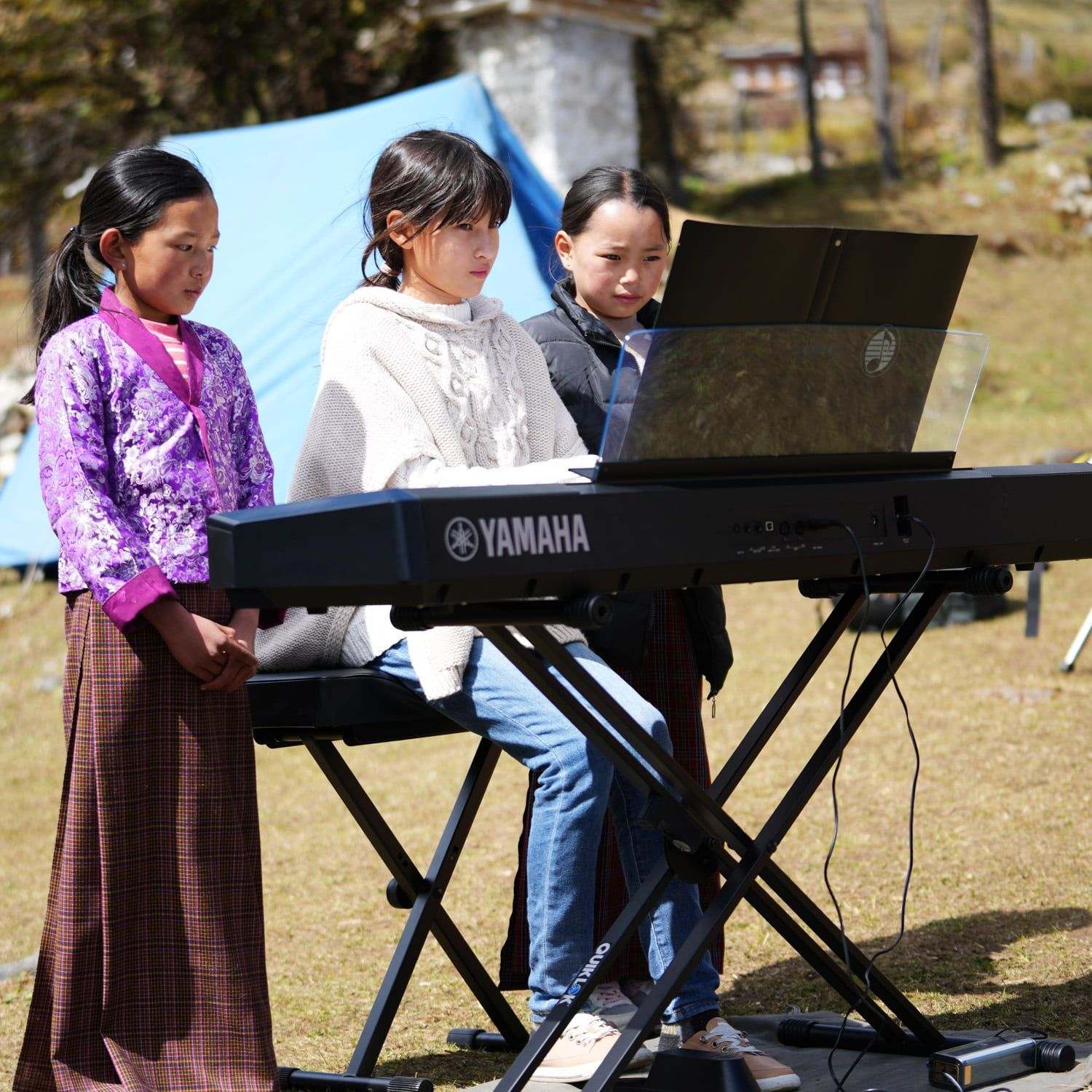 Children from Laya gathered around the keyboard at the Royal Highland Festival, filmed for The Girl and Her Piano