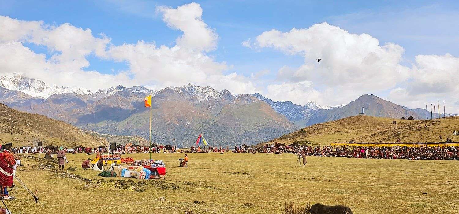 The Royal Highland Festival ground at Laya, Bhutan, at 4,000 metres, with the crowd gathered below the mountains, the setting of The Girl and Her Piano